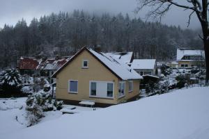a house covered in snow with trees in the background at Ferienhaus Maria Magdalena in Bad Lauterberg
