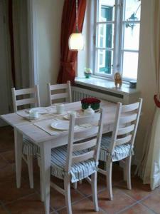 einen weißen Esstisch mit Stühlen und ein Fenster in der Unterkunft Deichhof Whg18 in Dunsum