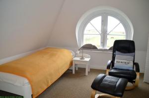 a bedroom with a bed and a chair in front of a window at Wohnen auf'm Lande HT 6 in Oldsum