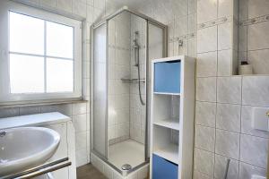 a white bathroom with a shower and a sink at Am Deich 14 in Zingst