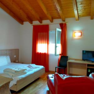 ポルデノーネにあるAl Cavaliereのベッドルーム1室(赤いカーテンとソファ付きのベッド1台付)