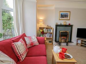 a living room with a red couch and a fireplace at Gillercombe in Bowness-on-Windermere