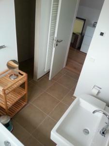 een badkamer met een witte wastafel en een tegelvloer bij Ostsee - Reetdachhaus Nr 34 "Caelestis" im Strand Resort in Heiligenhafen