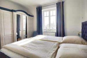 a bedroom with a large white bed with blue curtains at Villa Balticum, Whg 4 in Zingst