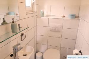 Baño blanco con aseo y lavamanos en Tolles Studio Apartment in Tossens für junge Paare, en Tossens