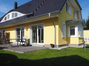 uma casa amarela com um alpendre e um deque em Grüner Winkel 32a em Zingst