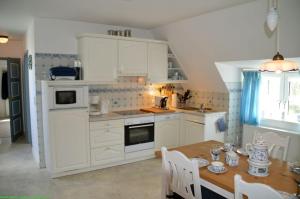 a kitchen with white cabinets and a wooden table at Haus 94-Whg OG in Oldsum