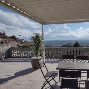 une terrasse avec une table, des chaises et une plante en pot dans l'établissement La magia delle Langhe appartamenti con vista, à Novello