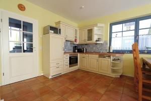 a kitchen with white cabinets and a tile floor at Uns Muschelhus in Zingst