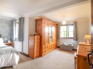 a bedroom with a bed and a wooden cabinet at 1 The Gardens in Stowmarket