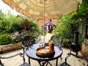a table with two wine glasses and an umbrella at 1 The Gardens in Stowmarket