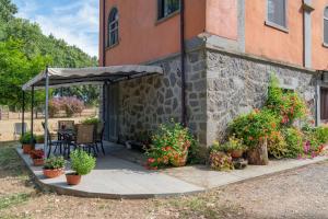 un patio con plantas y una sombrilla junto a un edificio en Casal Ponziani per Civita e Dintorni, en Bagnoregio