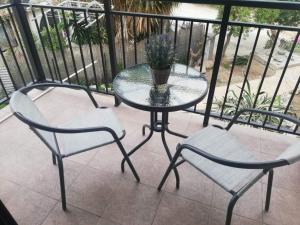 uma mesa de vidro e 2 cadeiras numa varanda em Cozy 1 bedroom apartment close to the beach em Pafos