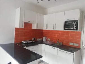 uma cozinha com armários brancos e uma parede de azulejos vermelhos em Cozy 1 bedroom apartment close to the beach em Pafos