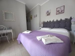 een slaapkamer met een paars bed met handdoeken erop bij Il Grifo in Sabaudia