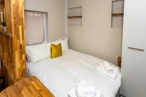 Dormitorio pequeño con cama blanca y almohada amarilla en Entire Luxury Studio in the Central of Reading en Reading