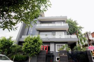 a gray building with a red door and trees at Hotel Kingston House in Lucknow