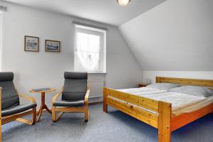 a bedroom with a bed and two chairs at Waldesruh - App 1 in Zingst
