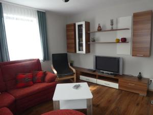 sala de estar con sofá rojo y TV en Ferienwohnung Dorfblick, en Kössern