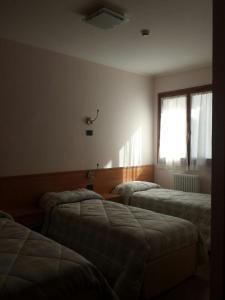 カナーレ・ダーゴルドにあるCasa Alpina Sacro Cuoreのベッド3台と窓が備わる客室です。
