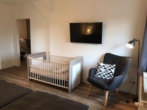 Zimmer mit einem Kinderbett, einem Stuhl und einem TV in der Unterkunft Ferienwohnung "Weitblick" in Schlichting in Schlichting