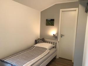 ein kleines Schlafzimmer mit einem Bett und einer Tür in der Unterkunft Ferienwohnung "Weitblick" in Schlichting in Schlichting