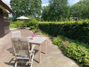 uma mesa de madeira com duas cadeiras e um guarda-sol em Het Beregoed em Malden