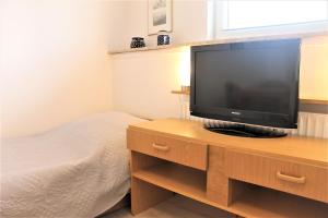 een slaapkamer met een flatscreen-tv op een houten standaard bij Haus Barbara - Schwimmbad und Sauna im Haus- Whg 7 in Grömitz