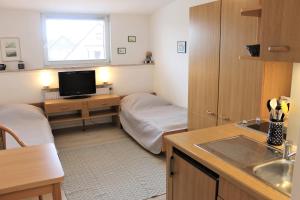 een kleine kamer met een bed en een keuken met een wastafel bij Haus Barbara - Schwimmbad und Sauna im Haus- Whg 7 in Grömitz