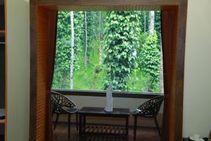 a window with a table and two chairs in a room at The Brook Resorts & Spa in Yercaud