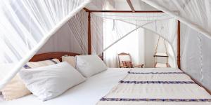 a bed with white sheets and pillows in a room at Jua House in Lamu
