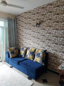 a blue couch in a living room with a stone wall at One Bedroom Beach Apartment/Pool/Free Wi-Fi in Mombasa