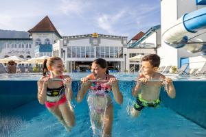 tres niños en el agua en una piscina en Schlosshotel Lacknerhof, en Flachau