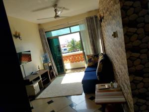 a living room with a blue couch and a sliding glass door at One Bedroom Beach Apartment/Pool/Free Wi-Fi in Mombasa