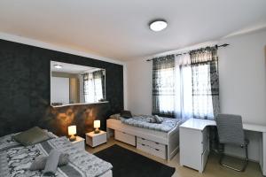 a bedroom with two beds and a desk and a mirror at Apartman SÙŠANJ in Opatija