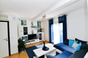 un salon avec un canapé bleu et une télévision dans l'établissement Apartman SÙŠANJ, à Opatija