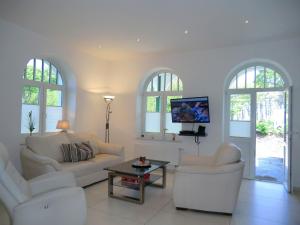 ein Wohnzimmer mit 2 weißen Sofas und einem TV in der Unterkunft Seestern - Whg 2 in Wyk auf Föhr