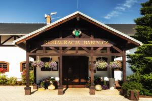 a building with a sign for a restaurant with flowers at Resort Dworzysko in Szczawno-Zdrój