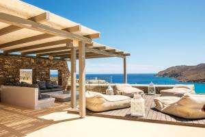 een gemeubileerde patio en de oceaan op de achtergrond bij Margi Villas in Mykonos-stad