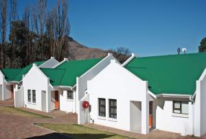 eine Reihe weißer Gebäude mit grünen Dächern in der Unterkunft Gable Cottages 3 in Clarens