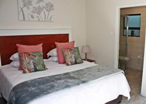 ein Schlafzimmer mit einem großen Bett mit roten Kissen in der Unterkunft Gable Cottages 3 in Clarens