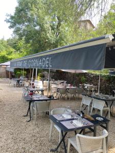 a group of tables and chairs under an umbrella at Restaurant et Chambres d'Hôtes La Ferme de Cornadel in Anduze