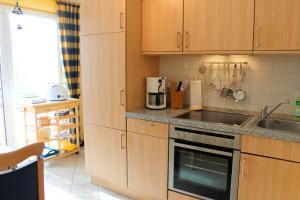a kitchen with wooden cabinets and a sink and a stove at Residenz am Kurpark - Whg 12 - familienfreundliche Wohnung, strandnah und zentral gelegen, WLAN in Grömitz