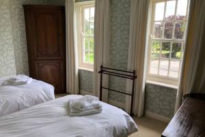 a room with two beds and two windows at Hall Cottage, Wighill near York and Leeds in Tadcaster