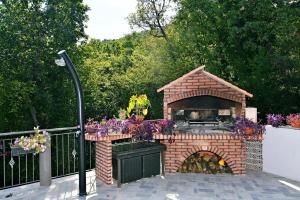 a brick pizza oven in a garden with flowers at Apartman SÙŠANJ in Opatija
