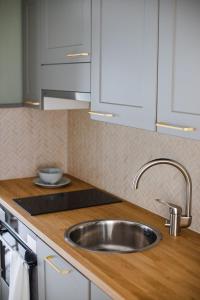 un fregadero de acero inoxidable en una cocina con armarios blancos en Krepelin Apartments, en Kristinestad