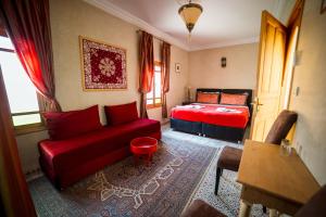 a living room with a red couch and a bed at Riad Inaka in Marrakesh