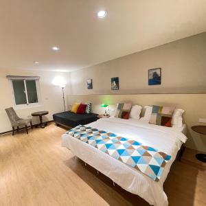a bedroom with a large bed and a couch at 墾丁聚點旅棧 2Ps Hotel in Kenting