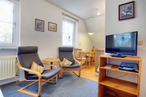 - un salon avec deux chaises et une télévision à écran plat dans l'établissement Waldesruh - App2, à Zingst