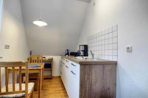 - une cuisine avec un évier, une table, une table et des chaises dans l'établissement Waldesruh - App2, à Zingst